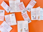 Der Flyer &bdquo;Wer betreut mein Kind?&ldquo; liegt in verschiedenen Sprach-Versionen teil aufgeklappt auf einer orangefarbenen Fl&auml;che. 